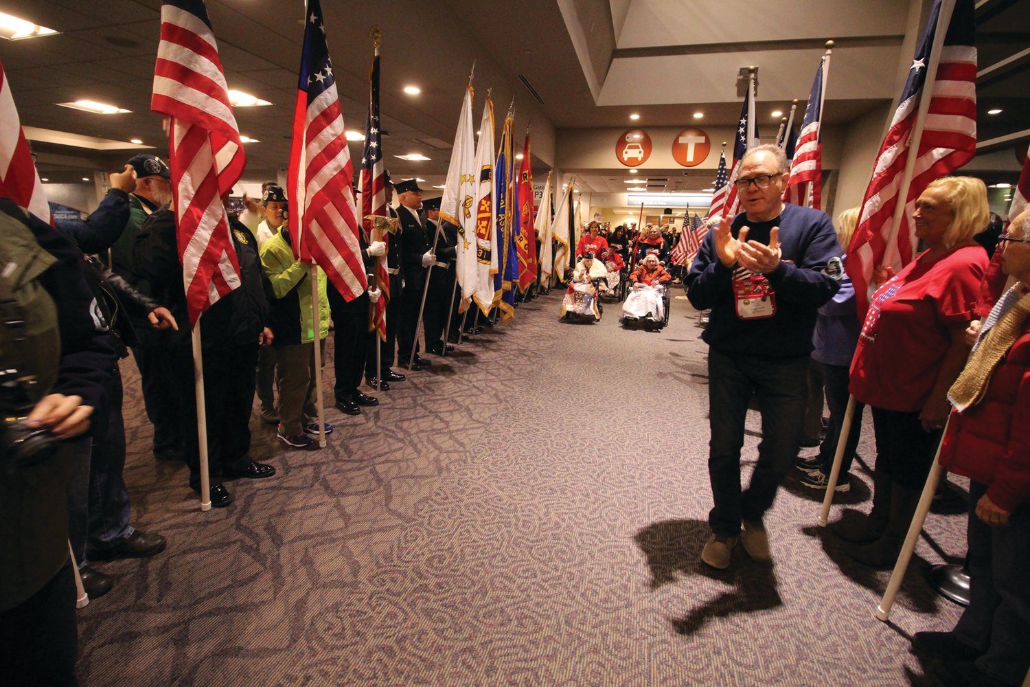 CHEERING THEM ON: George Farrell leads the way as members of the all women veterans flight held April 6, 2019 enter the terminal at Green Airport.